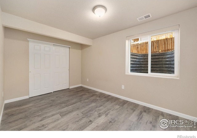 unfurnished bedroom with a closet, visible vents, baseboards, and wood finished floors