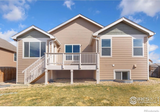 back of property with a wooden deck, a lawn, stairway, and fence