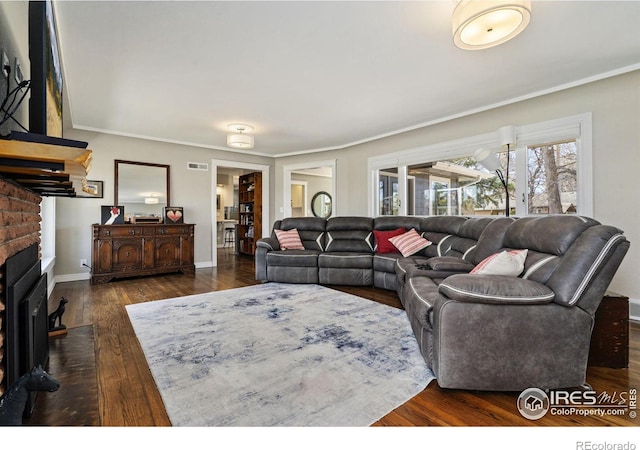 living area featuring dark wood finished floors, a brick fireplace, baseboards, and ornamental molding