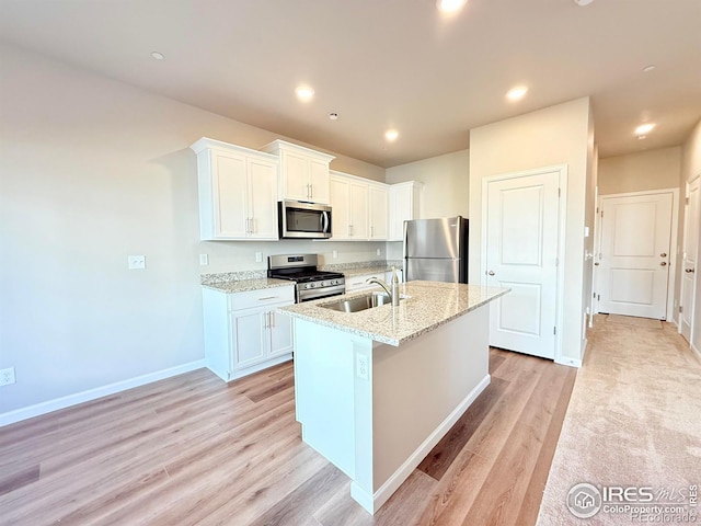 kitchen with light stone countertops, recessed lighting, appliances with stainless steel finishes, white cabinetry, and a sink