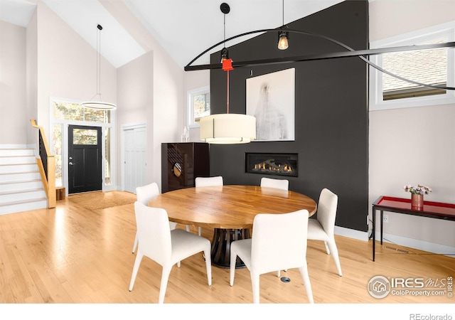 dining space featuring stairway, a healthy amount of sunlight, and wood finished floors