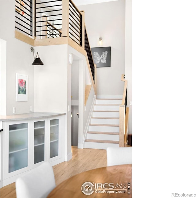 stairs featuring a high ceiling and wood finished floors