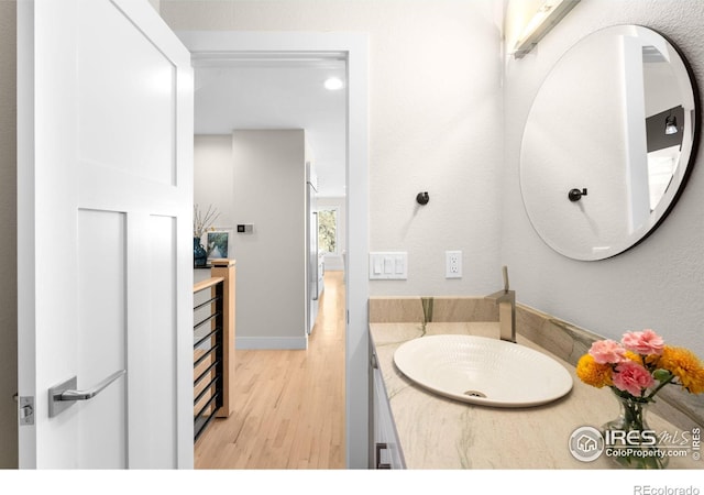 bathroom with vanity, wood finished floors, and baseboards