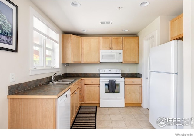 kitchen with a sink, visible vents, white appliances, and light brown cabinetry