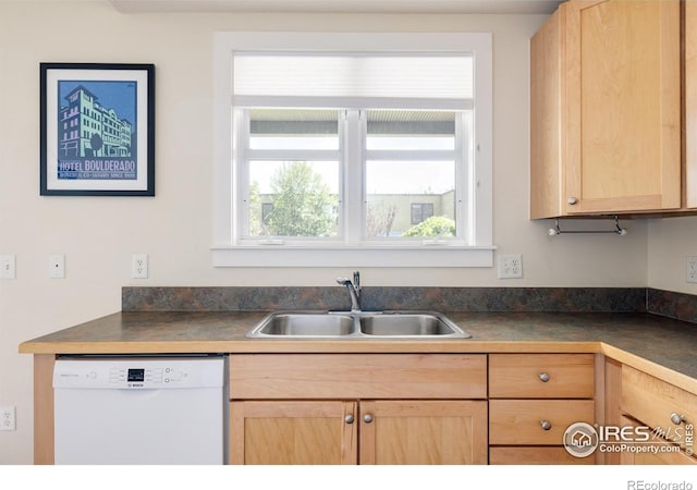 kitchen featuring dark countertops, light brown cabinets, white dishwasher, and a sink