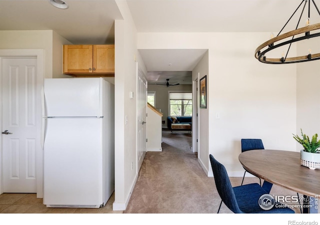 kitchen with light carpet, freestanding refrigerator, and baseboards