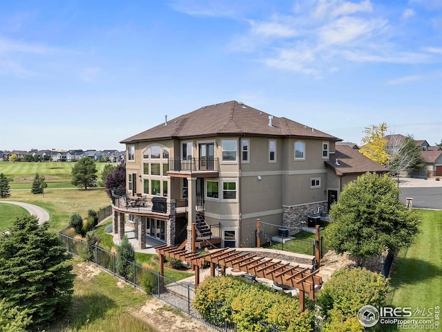 rear view of property with stucco siding, a fenced backyard, stairway, a balcony, and a patio area