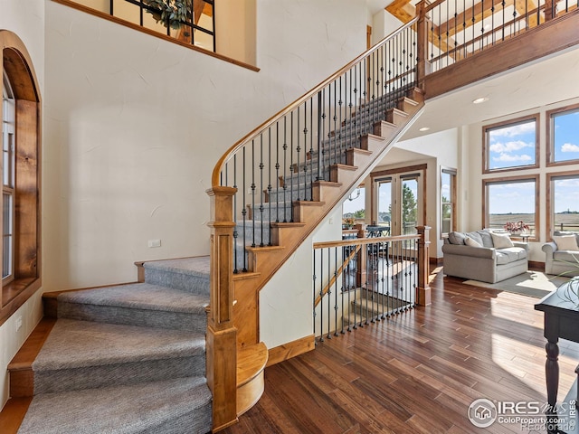 stairway with baseboards, a high ceiling, and wood finished floors