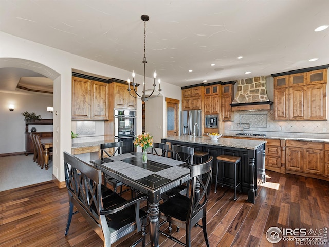 dining space featuring arched walkways, recessed lighting, dark wood finished floors, and baseboards