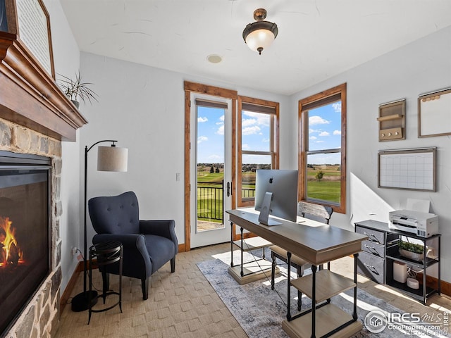 office space with baseboards and a stone fireplace