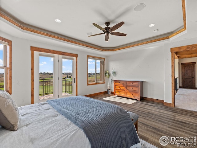 bedroom with a tray ceiling, wood finished floors, access to exterior, and baseboards