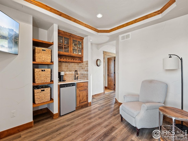 bar featuring wood finished floors, visible vents, a sink, stainless steel dishwasher, and a raised ceiling