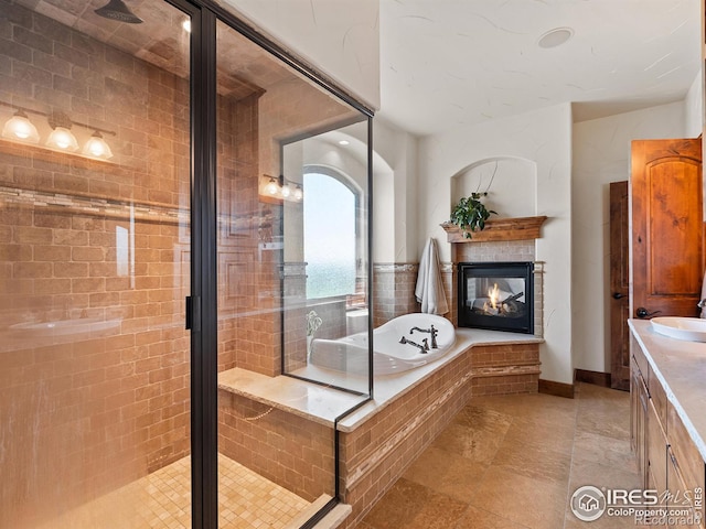 full bathroom featuring a multi sided fireplace, a stall shower, vanity, and a bath