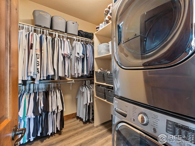 washroom with light wood-style floors, laundry area, and stacked washer / dryer