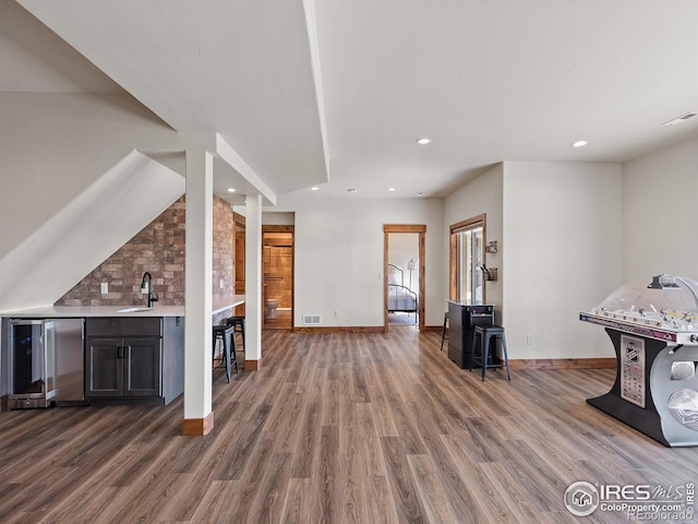 interior space with a sink, visible vents, baseboards, and wood finished floors