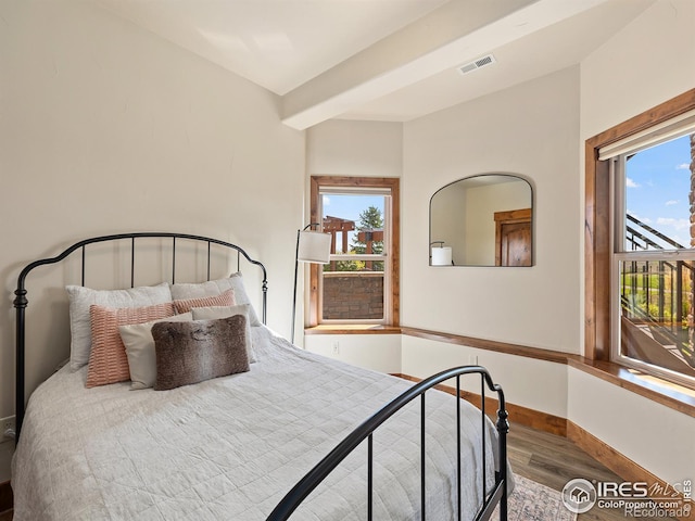 bedroom featuring visible vents, multiple windows, baseboards, and wood finished floors