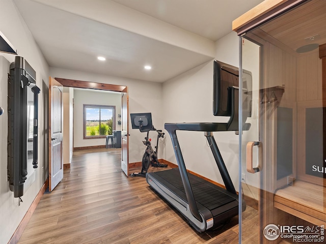 workout area featuring recessed lighting, light wood-type flooring, and baseboards