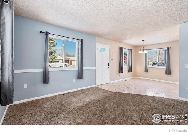 interior space featuring tile patterned flooring, baseboards, a textured ceiling, and an inviting chandelier