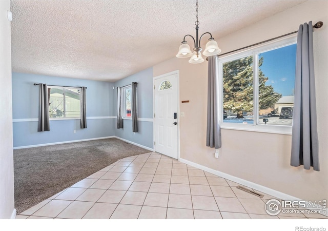 entrance foyer with baseboards, visible vents, a textured ceiling, light carpet, and a chandelier