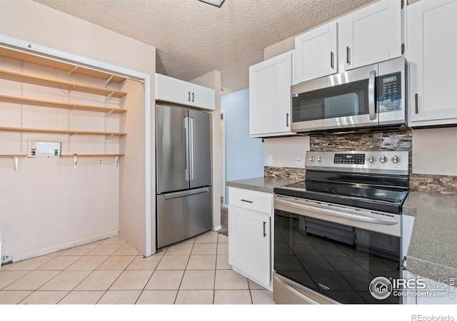 kitchen with light tile patterned floors, a textured ceiling, appliances with stainless steel finishes, and white cabinets