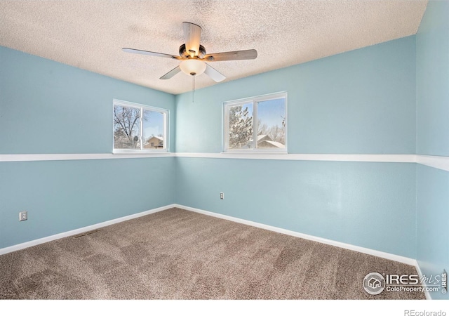 carpeted spare room featuring baseboards, visible vents, a textured ceiling, and a ceiling fan