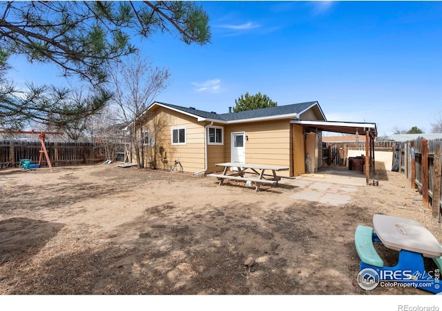 rear view of property with an attached carport and a fenced backyard