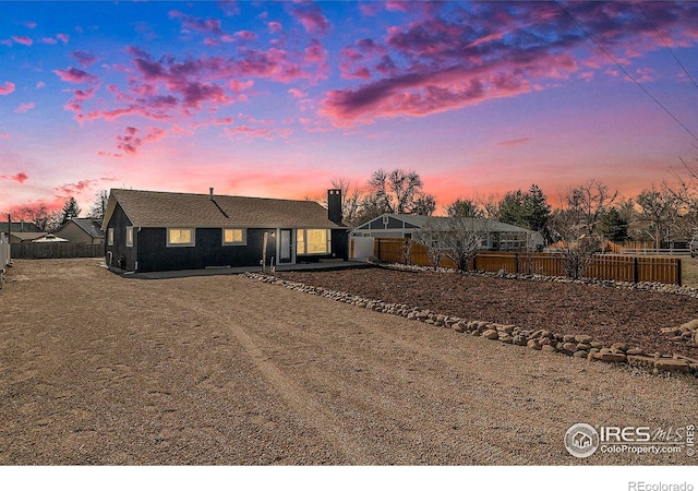 view of front of property featuring fence and dirt driveway