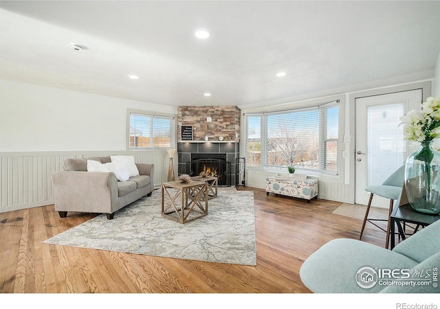 living area featuring recessed lighting, wood finished floors, a wainscoted wall, and a large fireplace