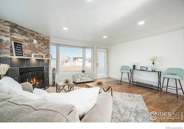 living room featuring recessed lighting, wood finished floors, baseboards, and a tile fireplace