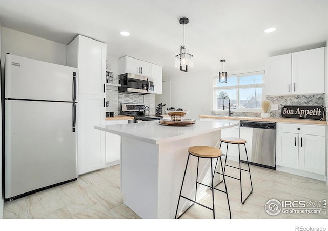 kitchen with white cabinetry, light countertops, a breakfast bar area, and stainless steel appliances