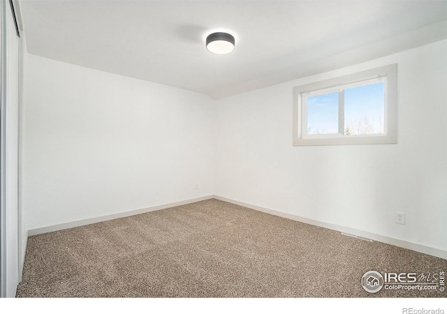 empty room featuring carpet flooring, visible vents, and baseboards