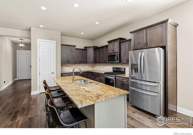 kitchen featuring a sink, dark brown cabinetry, light stone counters, and stainless steel appliances