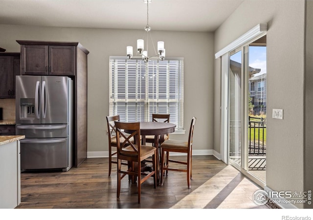 dining room featuring dark wood-style floors, a notable chandelier, and baseboards