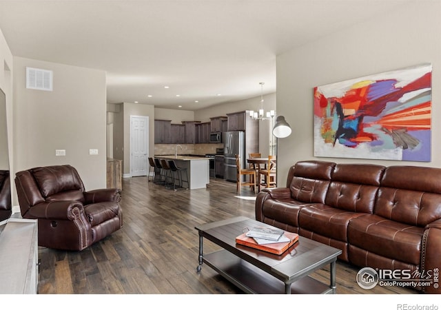 living room featuring dark wood-style floors, visible vents, recessed lighting, and a chandelier