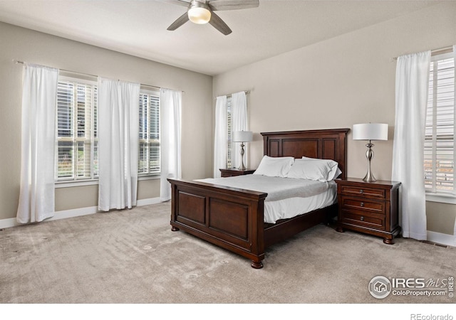 bedroom featuring baseboards, light colored carpet, and a ceiling fan