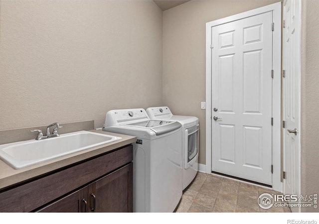 clothes washing area with cabinet space, independent washer and dryer, and a sink