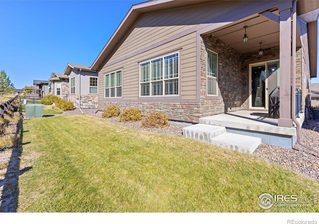 exterior space with stone siding, a lawn, and a patio