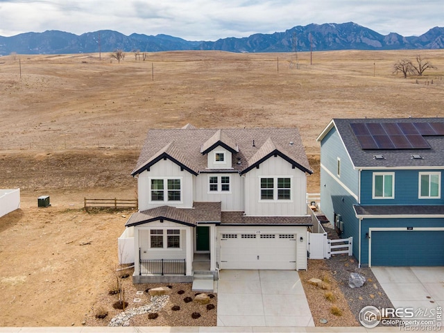 view of front of house featuring a mountain view, board and batten siding, driveway, and fence