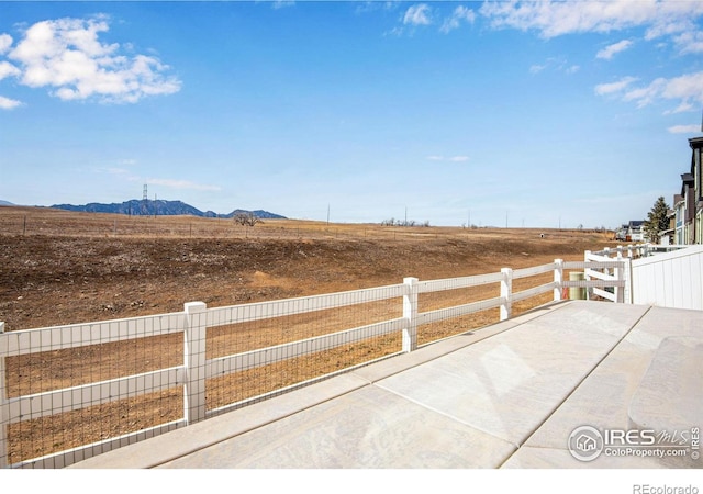 exterior space with a rural view, a mountain view, a patio, and fence