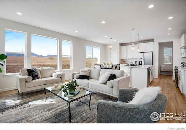 living room with recessed lighting, a mountain view, baseboards, and light wood-style floors