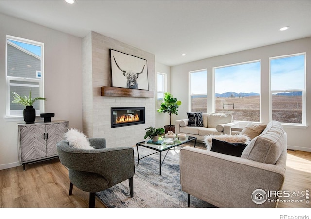 living room featuring a fireplace, recessed lighting, wood finished floors, and baseboards