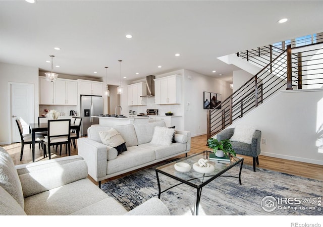 living area featuring recessed lighting, baseboards, light wood-style flooring, and stairs