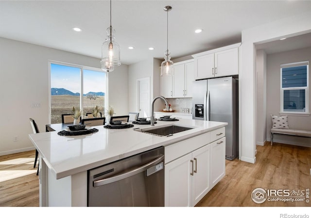 kitchen with a sink, white cabinetry, a mountain view, appliances with stainless steel finishes, and light wood finished floors