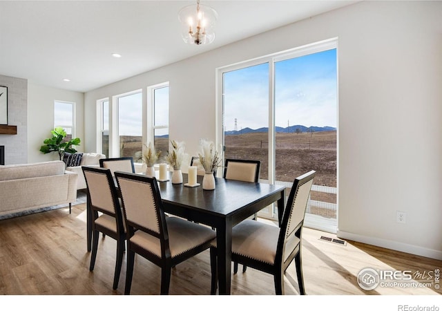 dining space featuring visible vents, an inviting chandelier, light wood-style floors, a mountain view, and a large fireplace