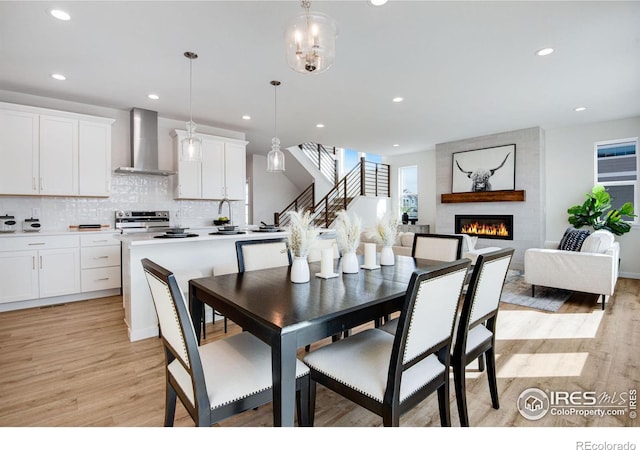 dining space with recessed lighting, light wood-style flooring, and a large fireplace