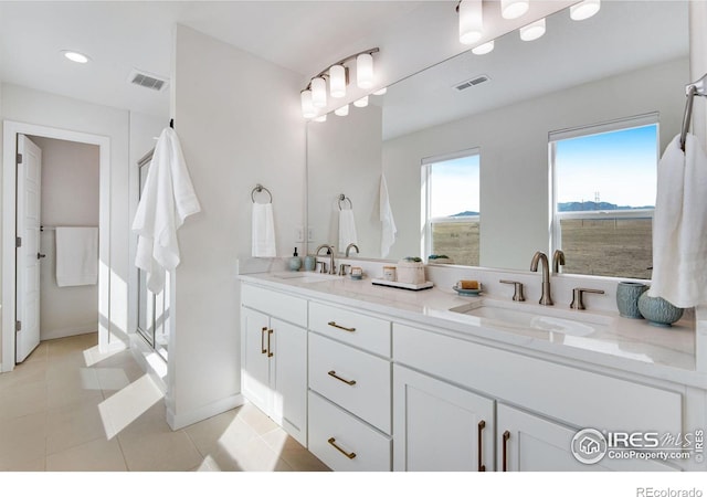 bathroom with a sink, visible vents, double vanity, and tile patterned flooring