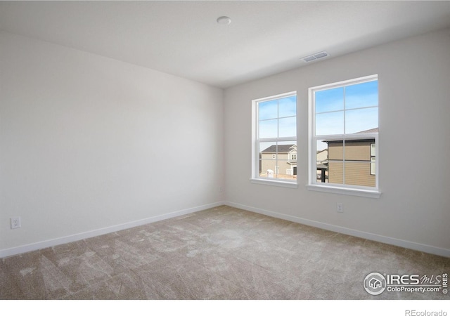 spare room featuring visible vents, carpet flooring, and baseboards