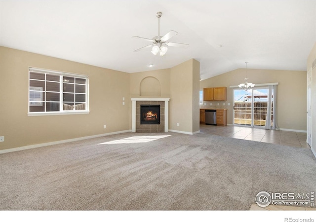 unfurnished living room with light colored carpet, lofted ceiling, ceiling fan with notable chandelier, a fireplace, and light tile patterned flooring