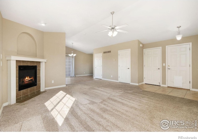 unfurnished living room featuring visible vents, ceiling fan with notable chandelier, carpet, a fireplace, and lofted ceiling