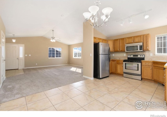 kitchen featuring light colored carpet, light countertops, vaulted ceiling, appliances with stainless steel finishes, and light tile patterned flooring